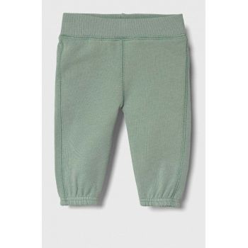 United Colors of Benetton pantaloni de trening din bumbac pentru bebeluși culoarea verde, cu imprimeu ieftini